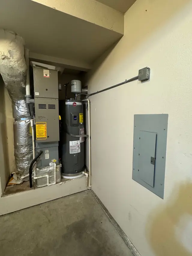 A new Rheem electric water heater installed in a closet beside the furnace, photographed by the customer